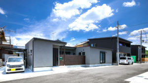 グレーのコの字形の家は、be-plusのパッシブデザインの家。コの字形の家は、中央から自然のエネルギーを部屋の中に通す。