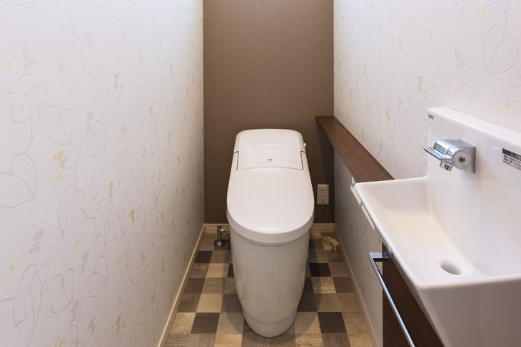 トイレの左右にオフホワイトにシルバーや白い植物柄のはいったスヌーピー壁紙を使用。