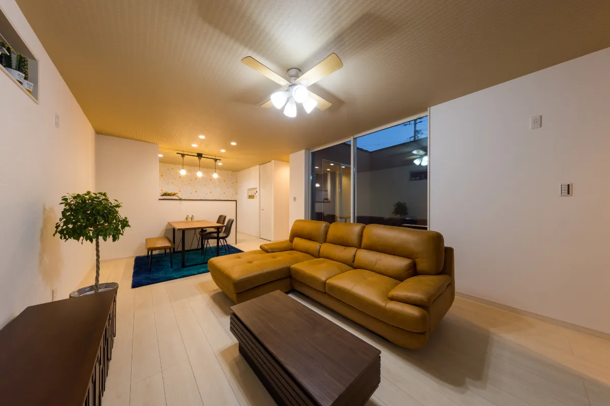 木製のダイニングテーブルとブラウンソファが並ぶ、温かみのあるリビングダイニング