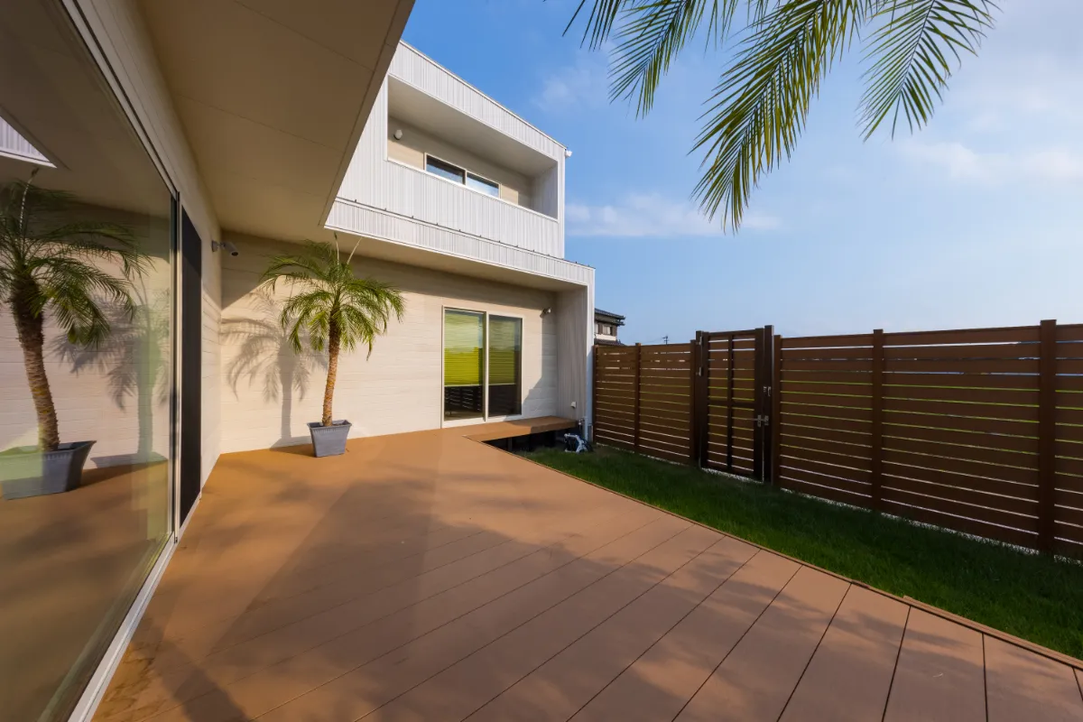 ヤシの木とウッドデッキがリゾートのような雰囲気を演出する日中のテラス全景