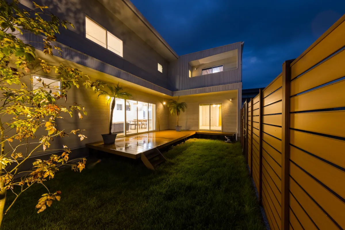 ゆったりとしたステップが庭とつながる空間を演出する夕暮れ時のテラス全景