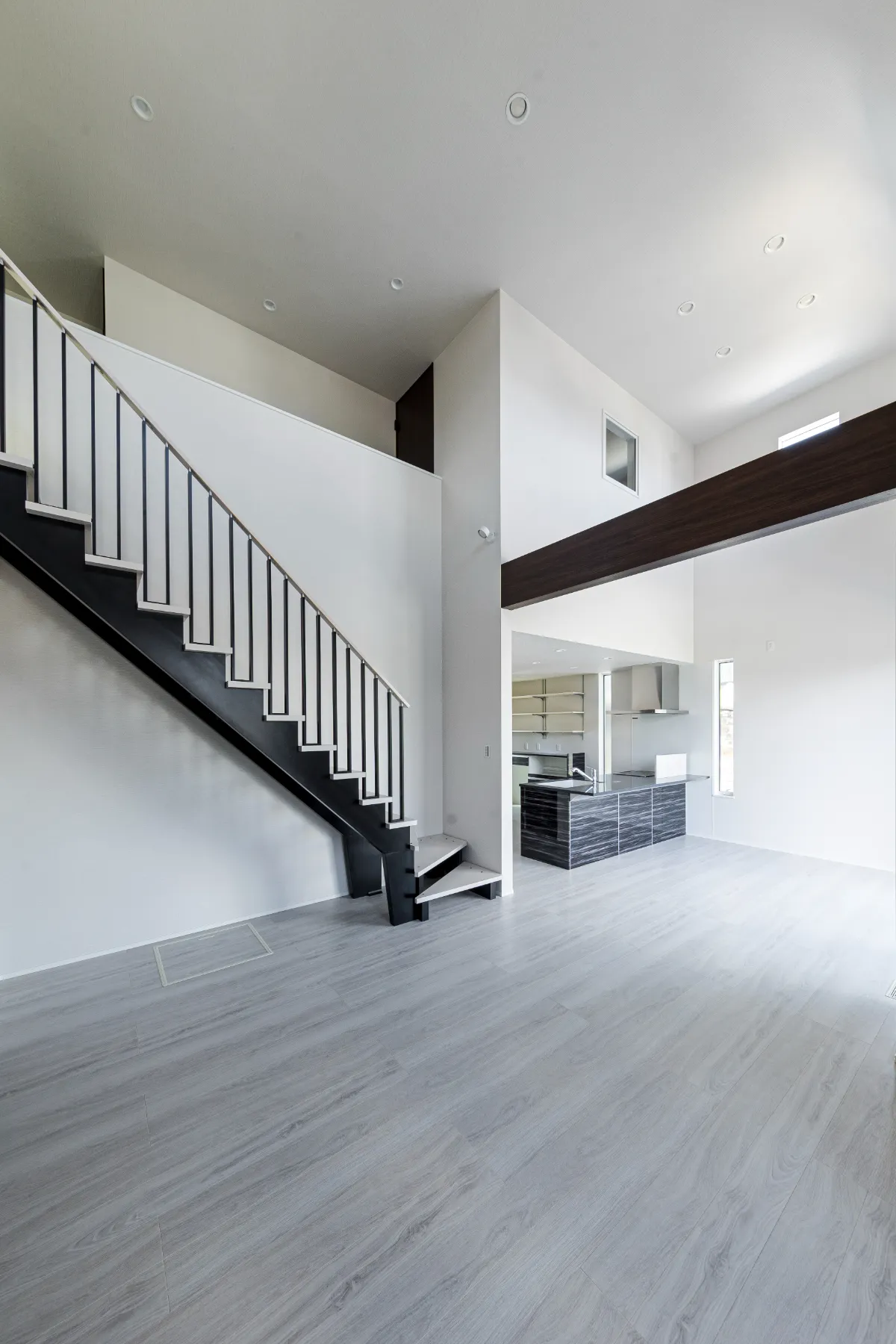 黒い階段と対面キッチンが調和した、シンプルで洗練されたリビングの一角