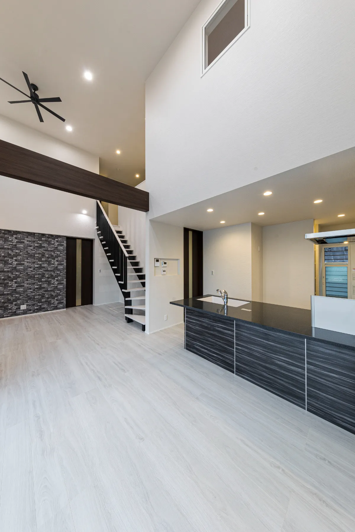 吹き抜け天井に設置された照明とファンが印象的なLDK空間