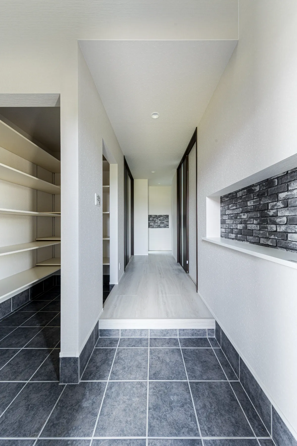 モノトーンのタイル床と白壁で構成された玄関ホール