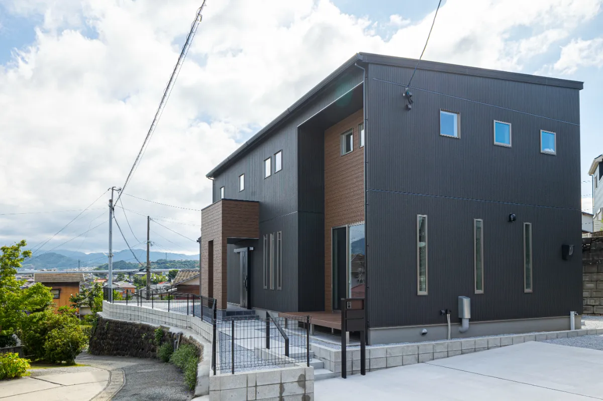 傾斜地に建つ、黒と木目を組み合わせたスタイリッシュな外観