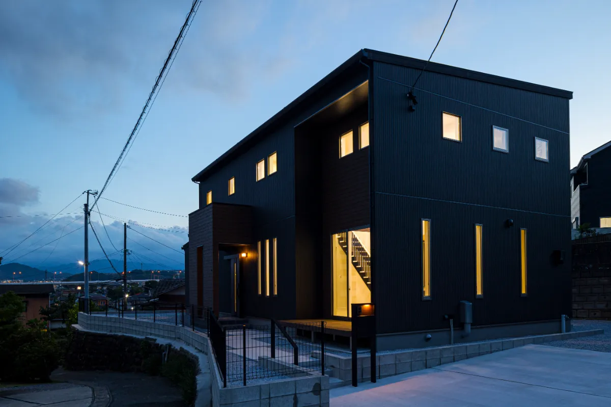 灯りがともる時間帯の住宅外観、落ち着いた街並みに溶け込む佇まい