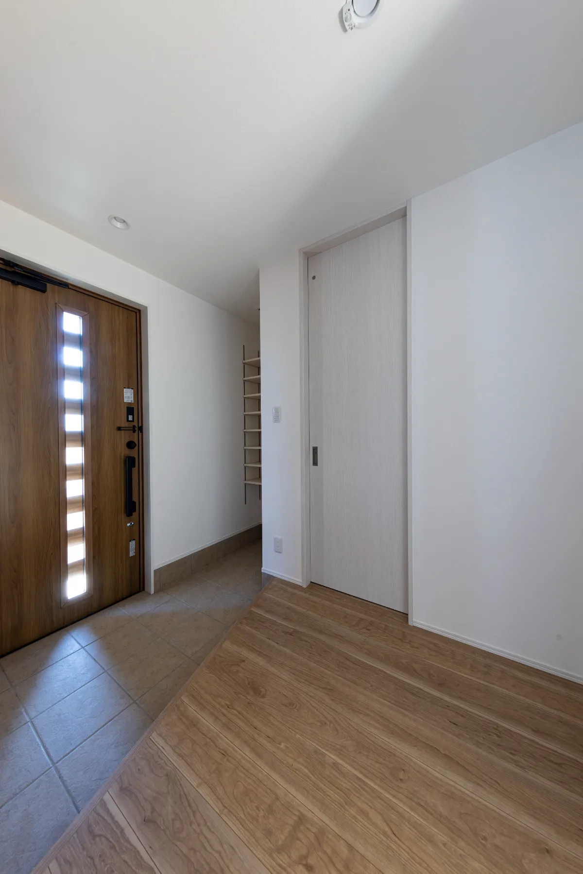 採光窓付きの木製玄関ドアが特徴的な玄関スペース