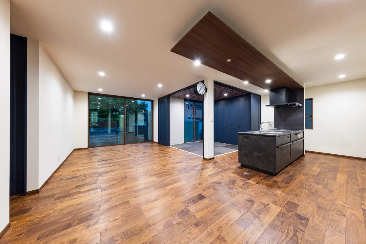 照明に照らされた木の床と落ち着きある空間が魅力の夜のリビング