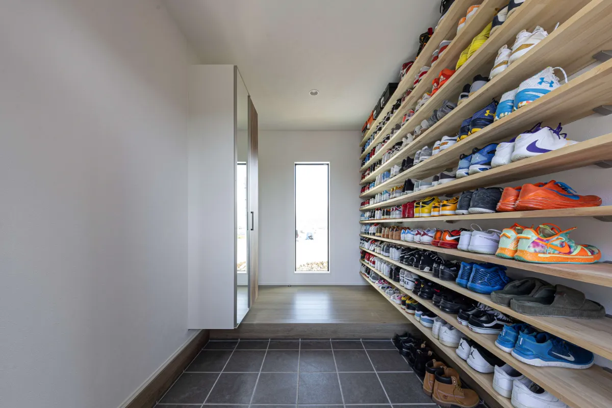 片側一面に設けられた可動棚にスニーカーが整然と並ぶ、大容量のシューズクローク