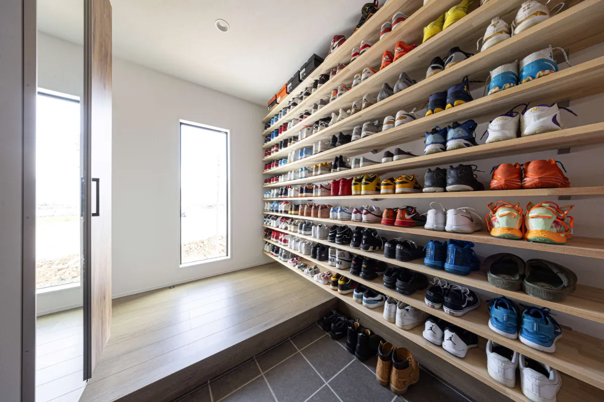 コレクションのようにスニーカーが並ぶ棚が印象的な開放感のある玄関空間