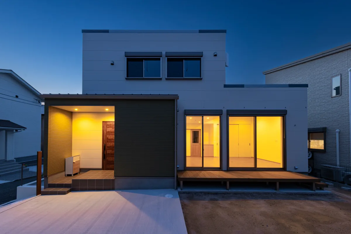 照明に照らされた玄関ポーチと室内の光が温かく浮かび上がる、夜の外観写真