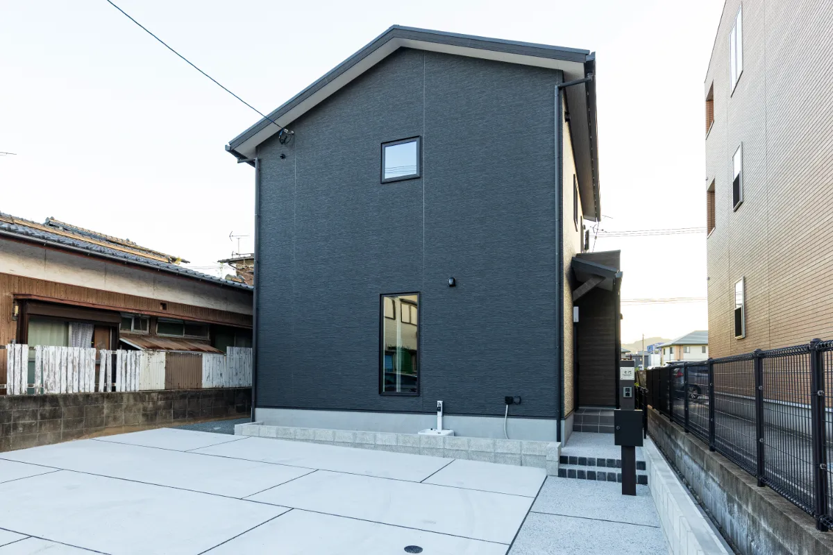 ダークグレーの外壁と縦長窓が特徴的な住宅の斜め外観