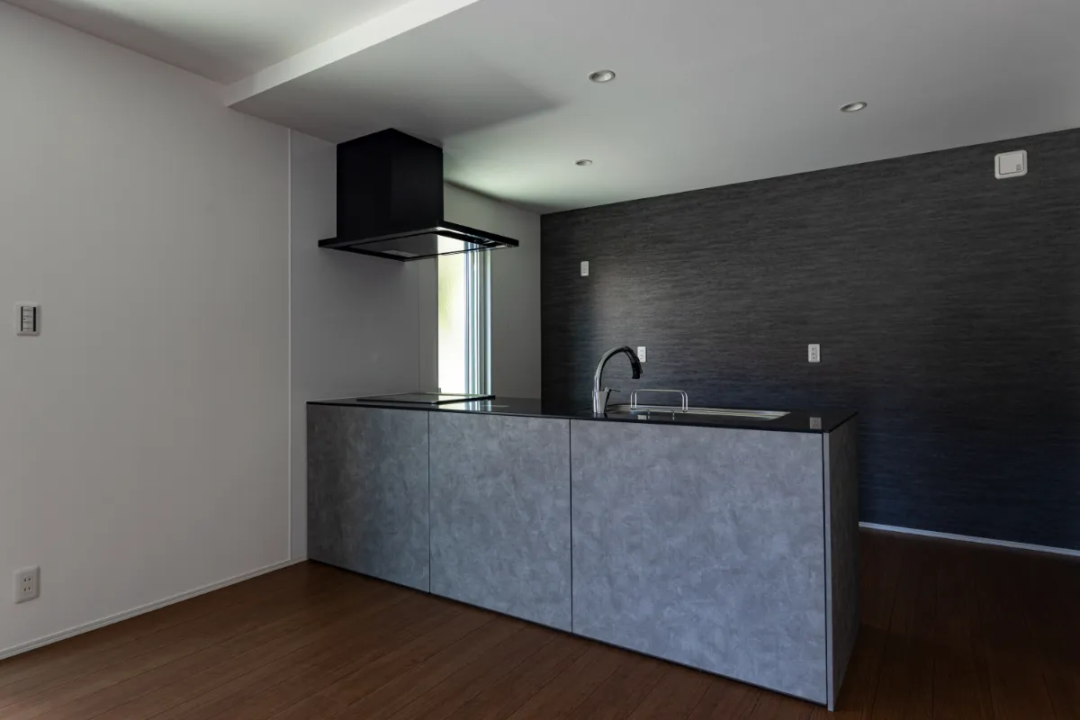 落ち着いたグレーの面材と黒のレンジフードが調和したキッチン