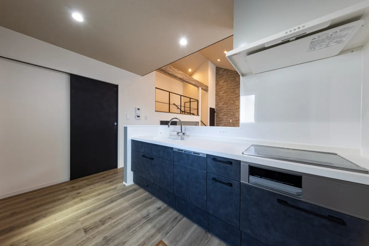 ネイビーのシステムキッチンが印象的な、白を基調とした清潔感あるキッチン空間
