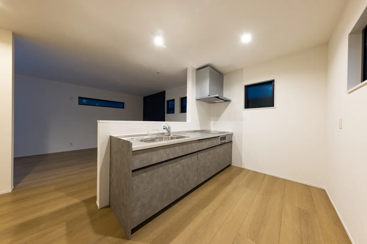 夜間照明に照らされたグレーの対面キッチン