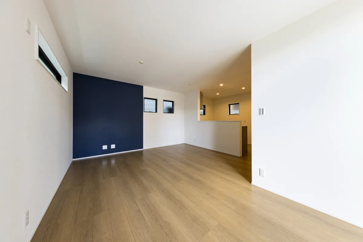 明るい床材とネイビーのアクセントクロスが調和する、シンプルかつモダンなLDK