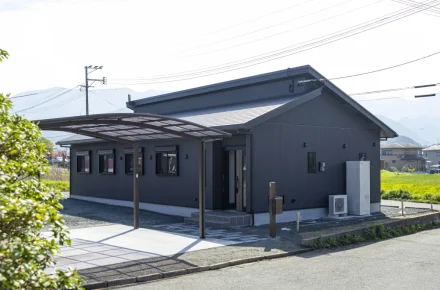 片流れ屋根と深い軒が印象的な、ダークトーンの外壁が引き締まった印象を与える平屋の外観