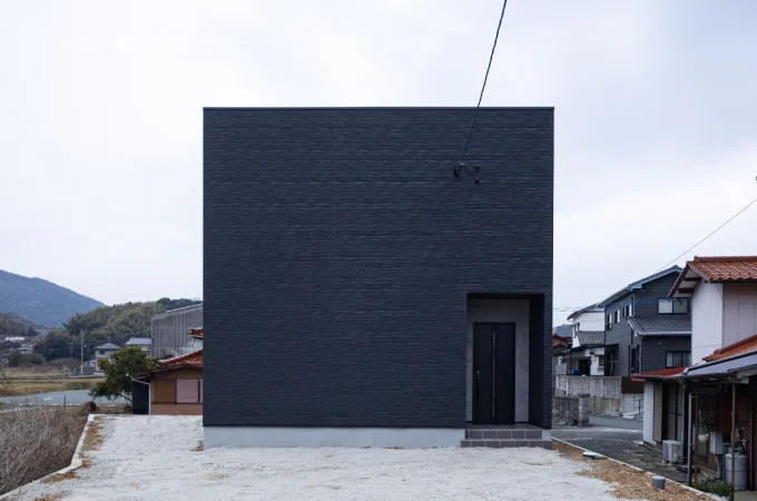 正面に窓のない、黒のキューブ型住宅の外観