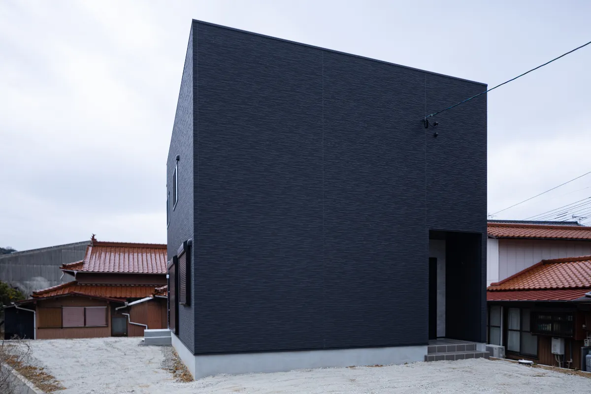 斜め前方から捉えた黒いキューブ型住宅