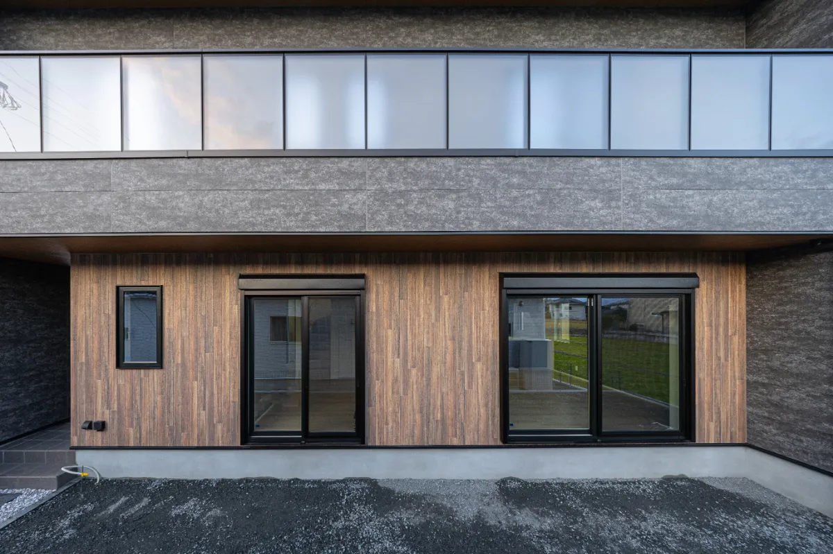 木目調の外壁と大きな掃き出し窓が並ぶ南側の外観。室内と外をゆるやかにつなぐ開放的なデザインです。