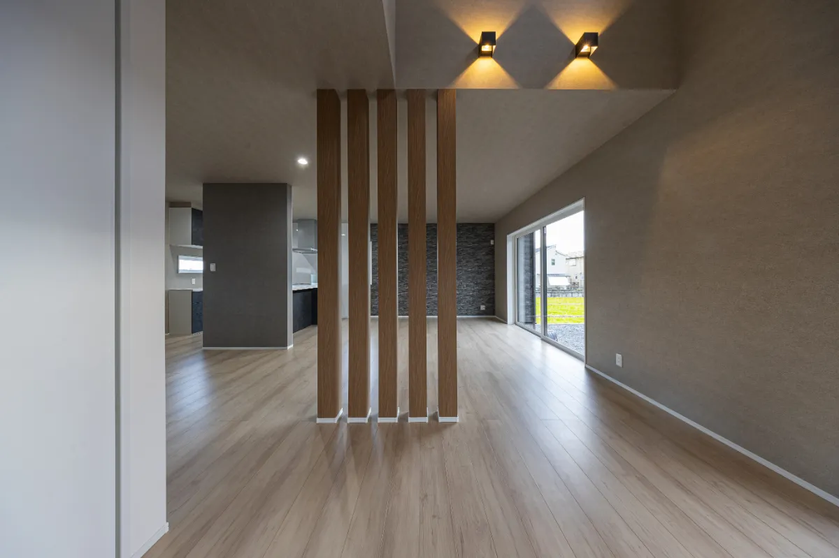 リビング中央に設けた木製の縦格子が空間をやわらかく仕切るデザイン。視線を遮りすぎず、ほどよい区切りをつくっています。