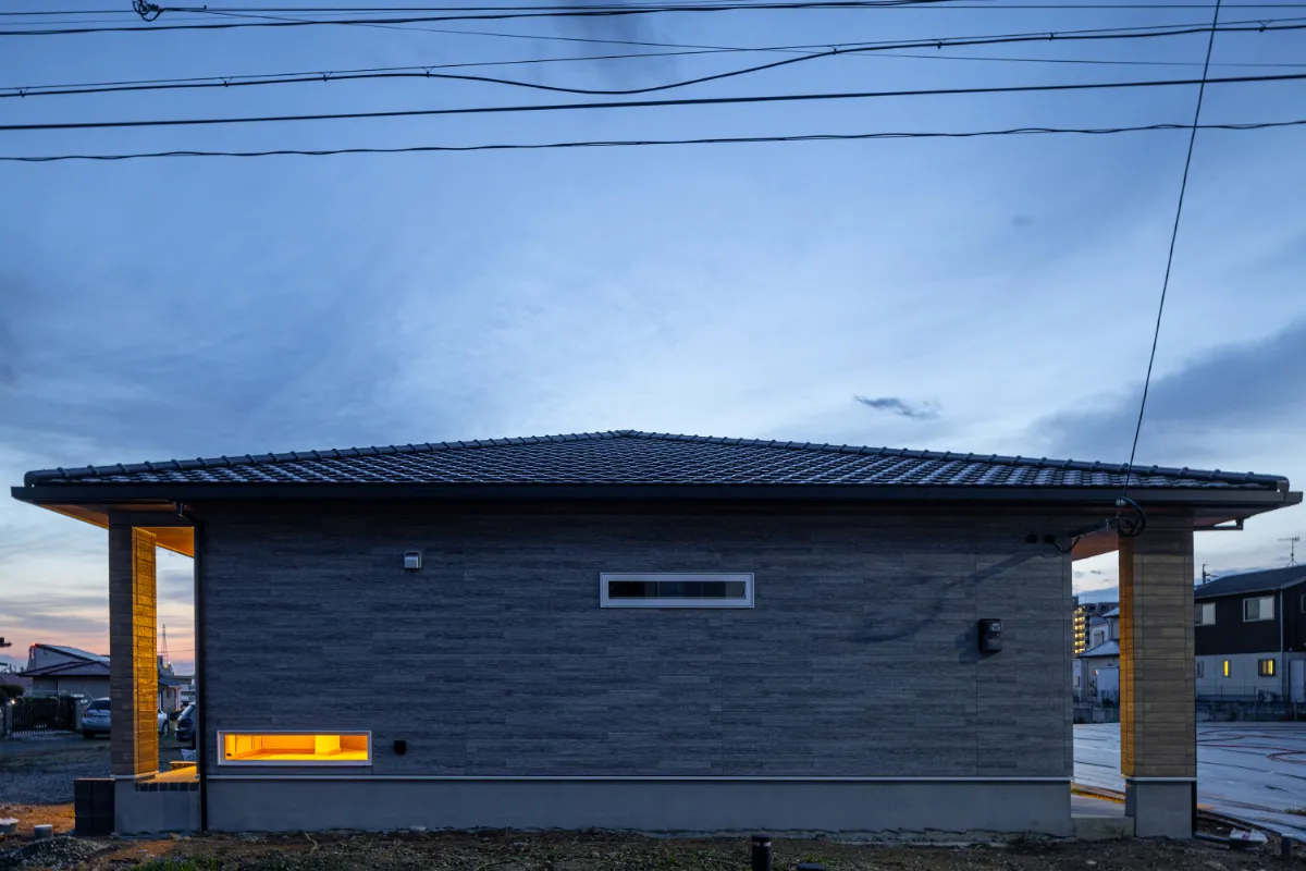 横長のスリット窓が印象的な外観側面。室内の明かりが外ににじみ、夜の街並みに自然と溶け込む佇まいです。