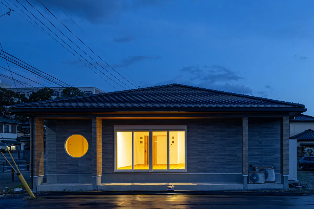 大きな掃き出し窓と丸窓が目を引く外観正面。室内の光があふれ、住まいの温もりが伝わってきます。