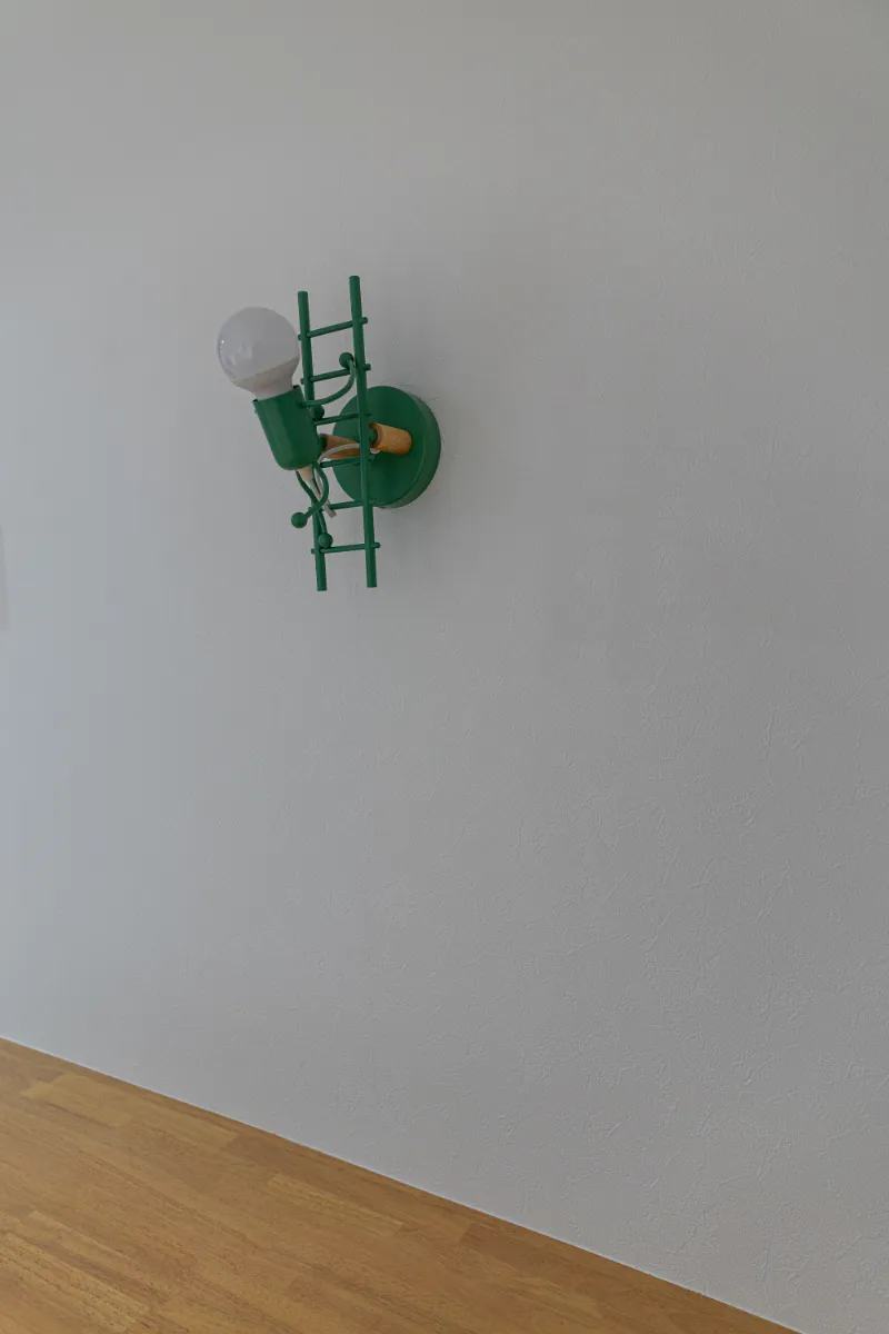 グリーンカラーが印象的なブラケット照明。シンプルな壁面に、遊び心のあるアクセントを加えています。