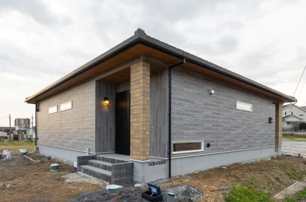 玄関ポーチの柱と外壁のコントラストが際立つ外観。軒の出をしっかりと確保し、重心の低い安定感ある佇まいです。