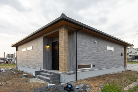 玄関ポーチの柱と外壁のコントラストが際立つ外観。軒の出をしっかりと確保し、重心の低い安定感ある佇まいです。