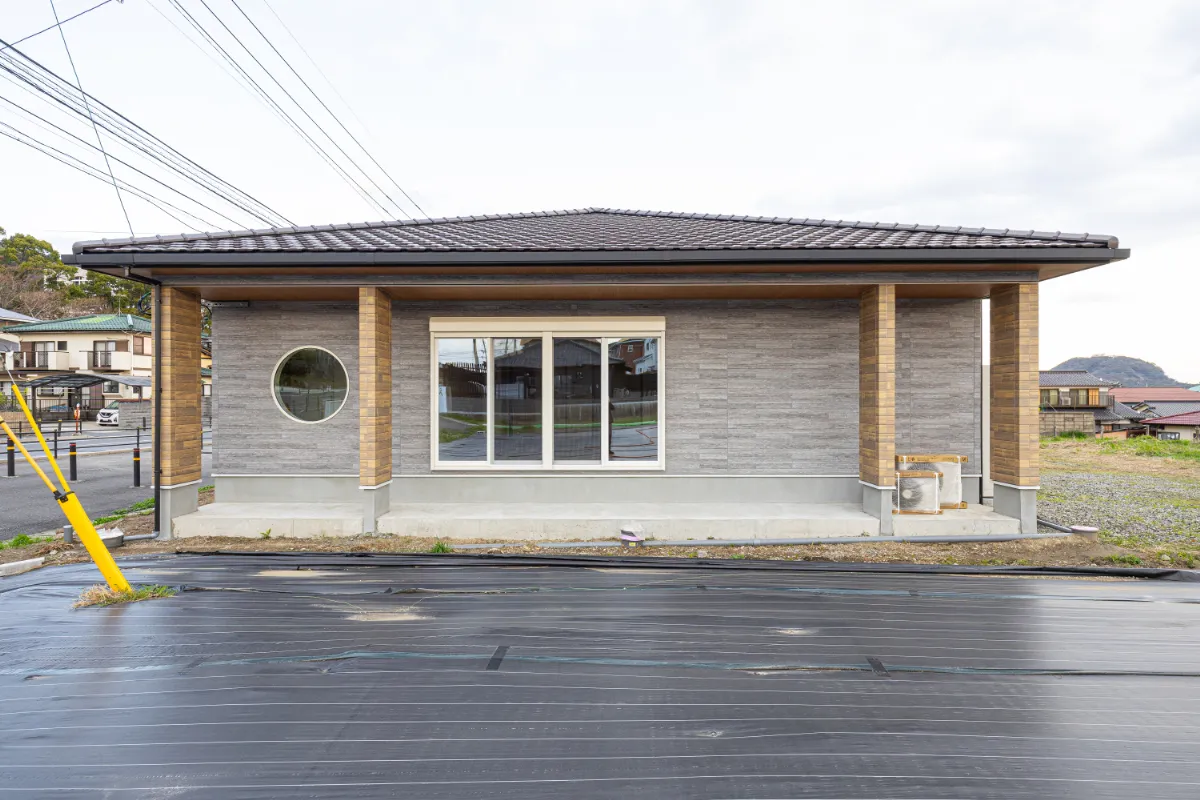 丸窓と大開口サッシがアクセントになった外観正面。木の温もりとシンプルなデザインが調和した平屋住宅です。