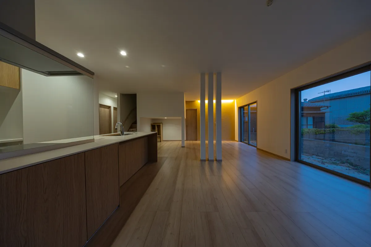 夕暮れ時のLDK。間接照明とダウンライトが空間をやさしく照らし、昼間とは違った落ち着きのある雰囲気に包まれています。