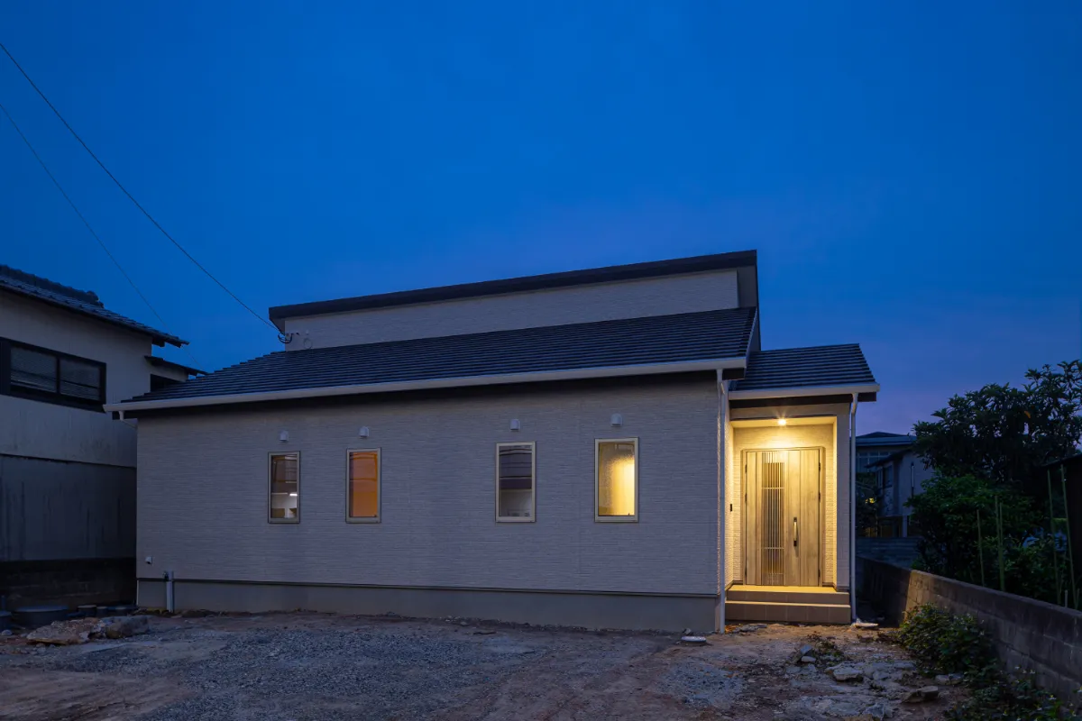 玄関ポーチを照らす照明が印象的な夕景。シンプルな外観の中に、落ち着きと安心感を感じられる佇まいです。