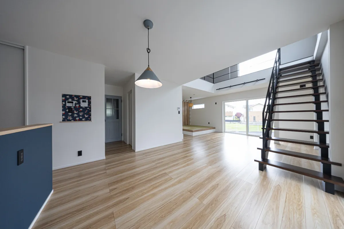 リビング階段と小上がりスペースがつながる開放的なリビング。大きな窓から自然光が入り、家族が自然と集まる明るい空間です。