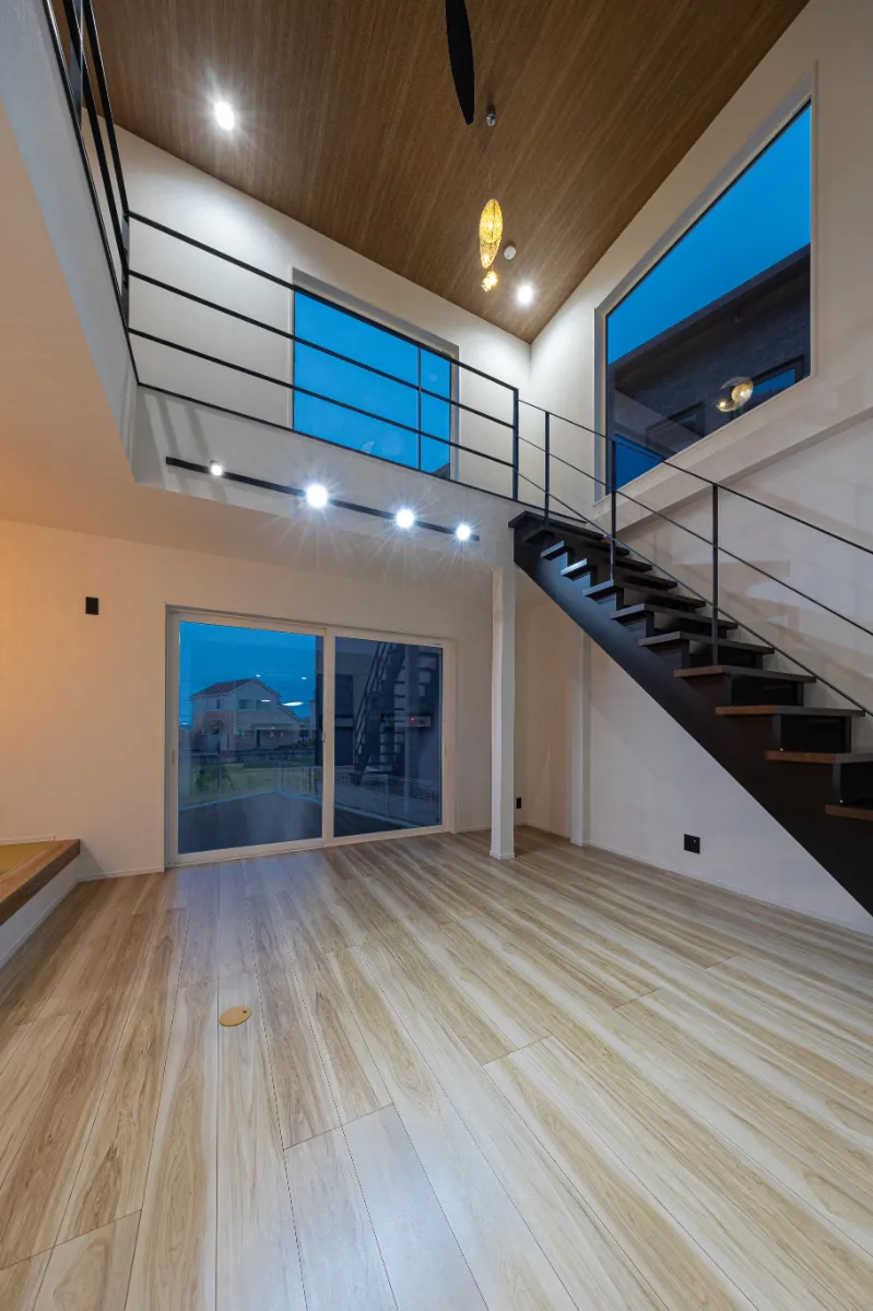 夜の吹き抜けリビング。間接照明が空間をやさしく照らし、昼間とは違った落ち着きのある雰囲気を演出しています。