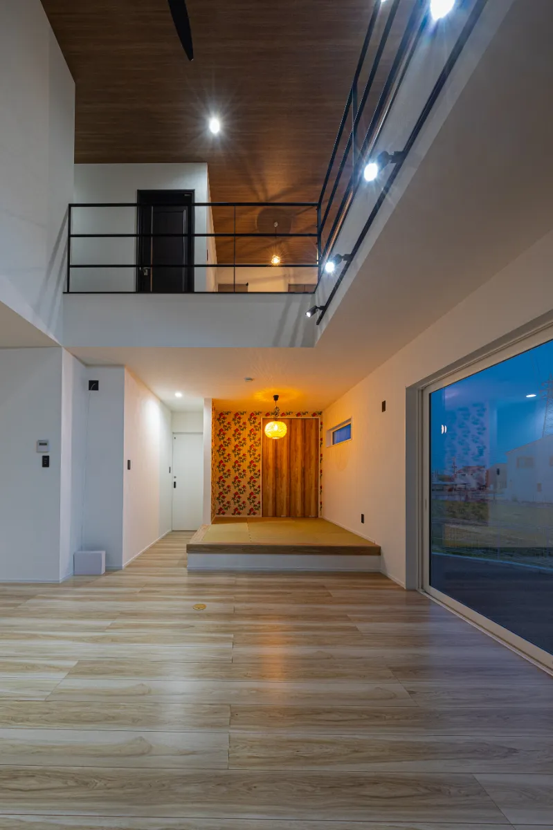 吹き抜けと小上がり和室を同時に望む夜の室内。上下階の光が重なり、立体感のある住まいの表情を感じられます。