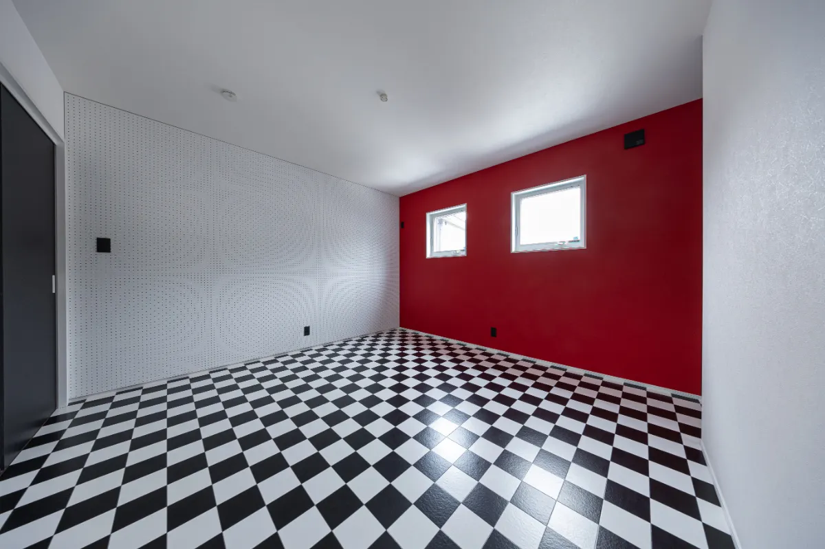赤いアクセントウォールと市松模様の床が目を引く洋室。大胆な配色で、個性的な空間になっています。