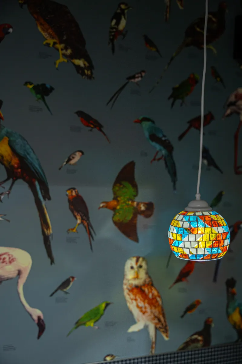 カラフルなモザイクガラスのペンダントライト。鳥柄のクロスと組み合わせ、空間に彩りと個性を添えています。