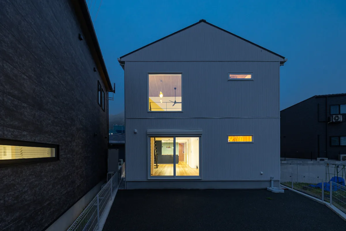 夜の庭側外観。室内のあかりが窓からやさしくこぼれ、昼間とは違った温もりのある表情を見せる住まいです。