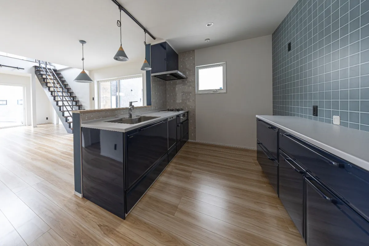 キッチン内側から見た調理スペース。タイル貼りの壁とブラックのキッチンが印象的で、作業しやすさとデザイン性を兼ね備えています。