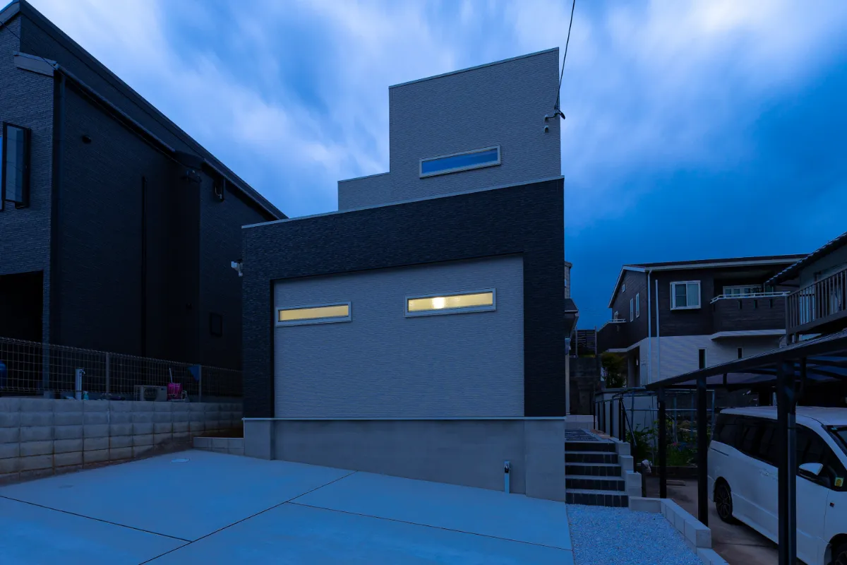 シンプルな箱型フォルムに、やさしい室内の灯りが浮かび上がる夕景の外観。落ち着いた配色が街並みに溶け込みます。