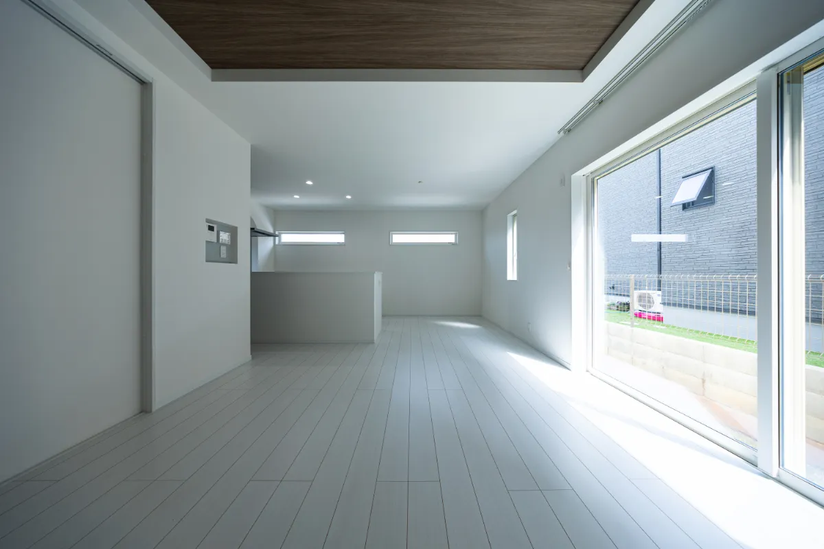 昼間のリビング。大きな窓からたっぷりと光が入り、白い床に明るさが広がる、爽やかな印象の空間です。