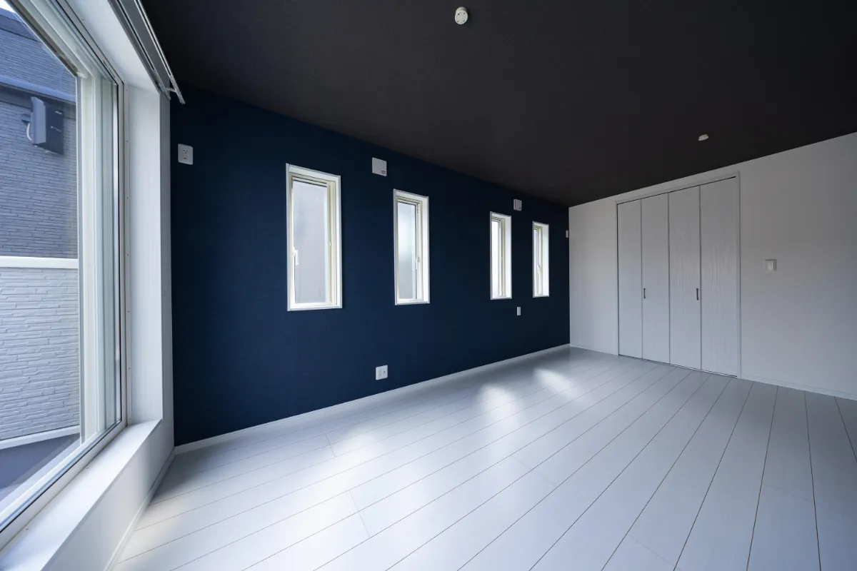 ネイビーのアクセントクロスと縦長窓が並ぶ洋室。白い床とのコントラストで、すっきりとした印象に仕上げています。