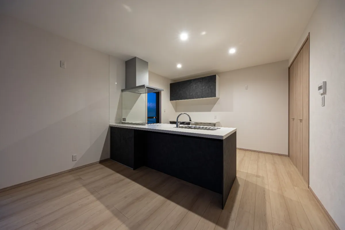 夜のキッチンの様子。落ち着いたトーンの面材とやわらかな照明が、くつろぎの時間を演出します。