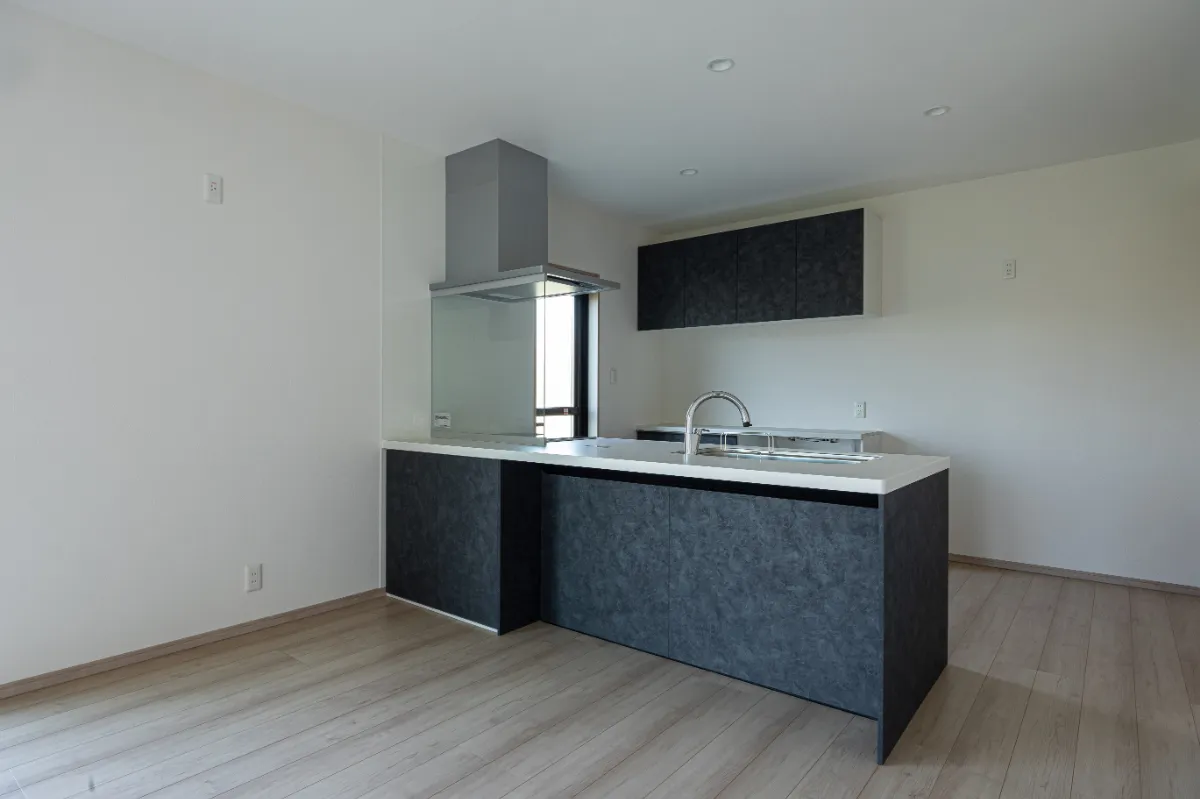 黒系面材と白い天板を組み合わせたキッチン。開放的なLDKとつながり、家族の様子を感じながら調理できるレイアウトです。